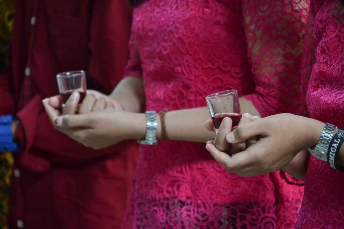 Frauenhände halten ein kleines Glas mit Wein