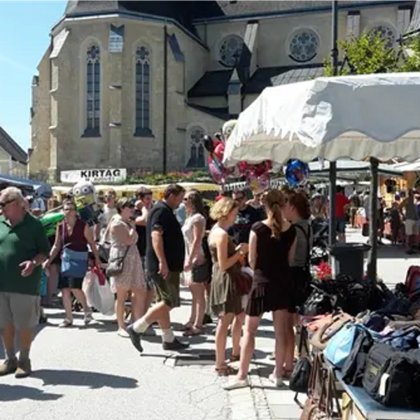 Leute am Kirtag, rechts Kirtagstand, im Hintergrund die Kirche