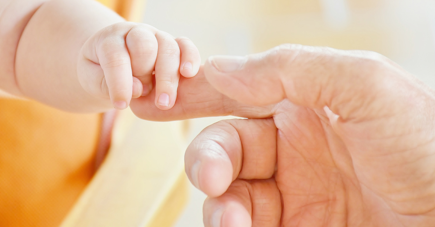 Eine Kinderhand und eine Erwachsenenhand berühren sich