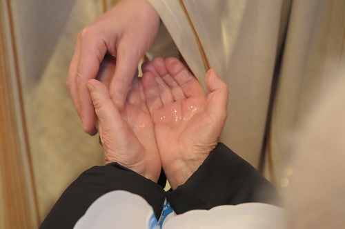 Priester salbt Hände