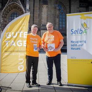 Bischof Manfred Scheuer und Kabarettist Günther Lainer in den Gute-Tage-T-Shirts vor dem Mariendom beim Start der neuen österreichweiten Dachmarke für Senior:innenbildung.