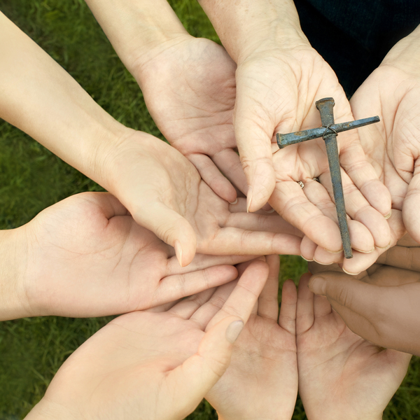 'Hands from people of all ages from children and teenagers to adults and the elderly, hands holding a handmade cross, made from old nails (shallow DOF with focus on the cross). Please see some similar pictures from my portfolio:'
