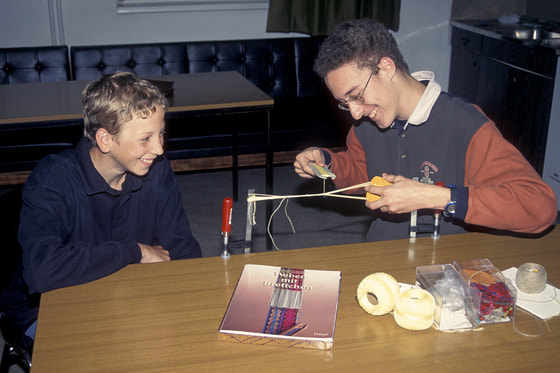 Die Runde webt Armbänder mit der uralten Kärtchen Methode (vgl. Oseberg Schiff)