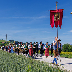 F26-06-04_4290_Fronleichnamsprozession mit Fahnen - Musikkapelle - Goldhaubenfrauen - Himmel am Rueckweg