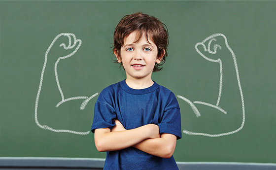 Strong child with muscles drawn on chalkboard in elementary school