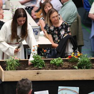 Eine Ministrantin streut Samen ins Blumenbeet