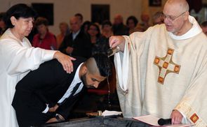 Joan Leo Ali empfängt das Sakrament der Taufe. Links seine Taufpatin Maria Scholl, rechts Pfarrer Franz Zeiger.