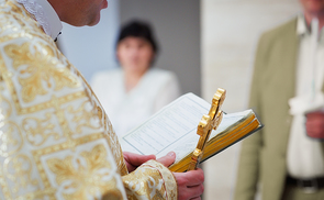 Beautiful golden cross in male hands of priest wearing gold robe on ceremony in christian cathedral church, holy sacramental event. Priest Holding A Bible