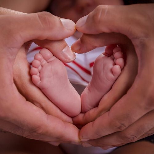 Babyfüße gehalten von 2 Paar Händen