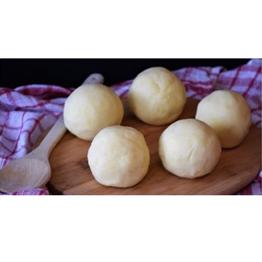 auf einem Holzbrett liegen ein Kochlöäffel und frisch gewuzelte Knödel