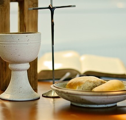 Kelch und Brot vor einem Kreuz