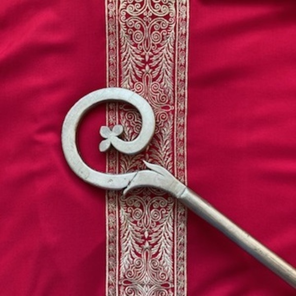 Bischofsstab liegt auf rotem goldbesticktem Gewandestickten