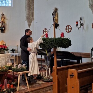 Ministrant Gabriel entzündet mit seinem Vater die erste Kerze.