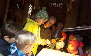 Steinmetzmeister Gerhard Fraundorfer mit seinen kleinen GehilfInnen beim Einmeißeln des Kreuzes in den neuen Altar.
