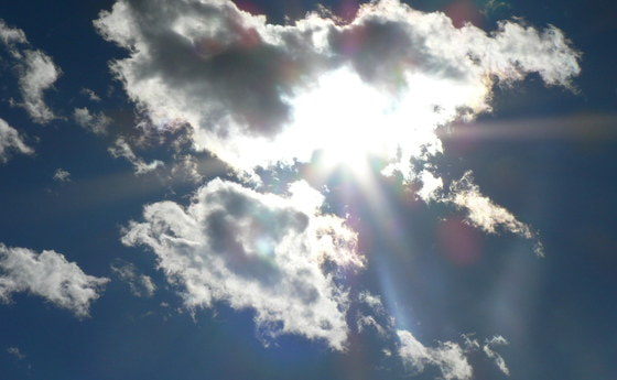 Die Sonne hinter den Wolken am Himmel erahnen. 