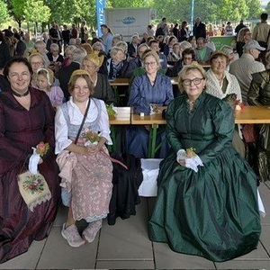 einige Goldhaubenfrauen beim Juniafest sitzend auf Bierbänken