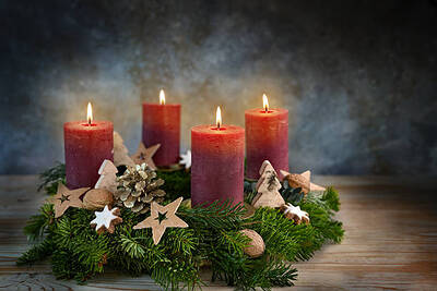 Four red candles on an Advent wreath, all are lit for the fourth advent, small stars, cookies and nuts as Christmas decoration, dark bluish background, copy space, selected focus, narrow depth of field