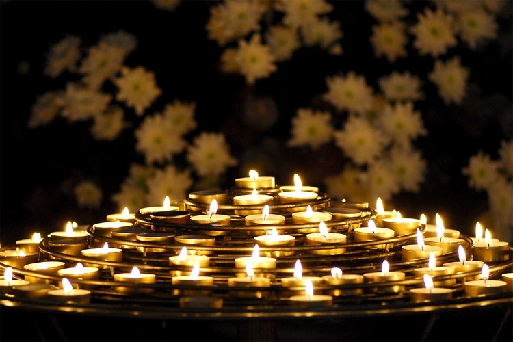Teelichter auf spiraligem Metallgestell,  im Hintergrund sieht man zart weiße Blumen, die wie Sterne wirkenp