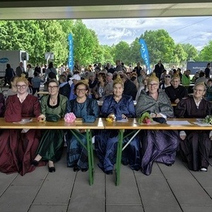 einige Goldhaubenfrauen beim Juniafest sitzend auf Bierbänken