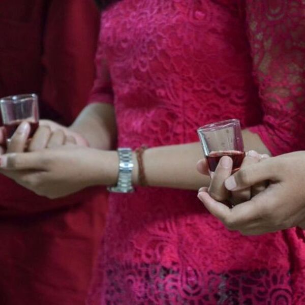 Frauenhände halten ein kleines Glas mit Wein