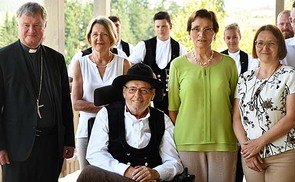 Bischof Manfred Scheuer, Visitatorin Brigitte Gruber-Aichberger, vorne Firmengründer Johann Buchner, seine Frau Hermine Buchner und Bernadette Buchner; im Hintergrund Mitglieder der „Buchner-Musi“.