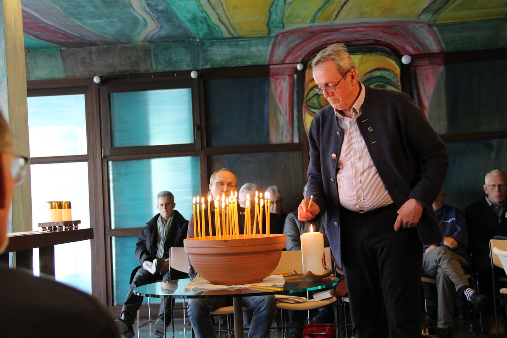 Die Teilnehmer der Konferenz entzünden eine Kerze im Rahmen der Friedensandacht