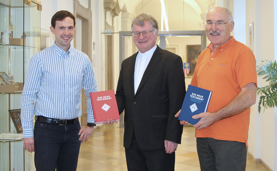 Franz Kogler und sein Nachfolger Reinhard Stiksel vom Bibelwerk Linz übergeben das Neue Testament an Bischof Manfred Scheuer.