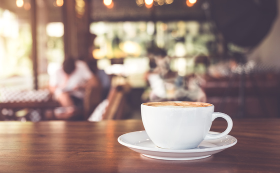 Cup of hot coffee on table in cafe with people. vintage and retro color effect - shallow depth of field