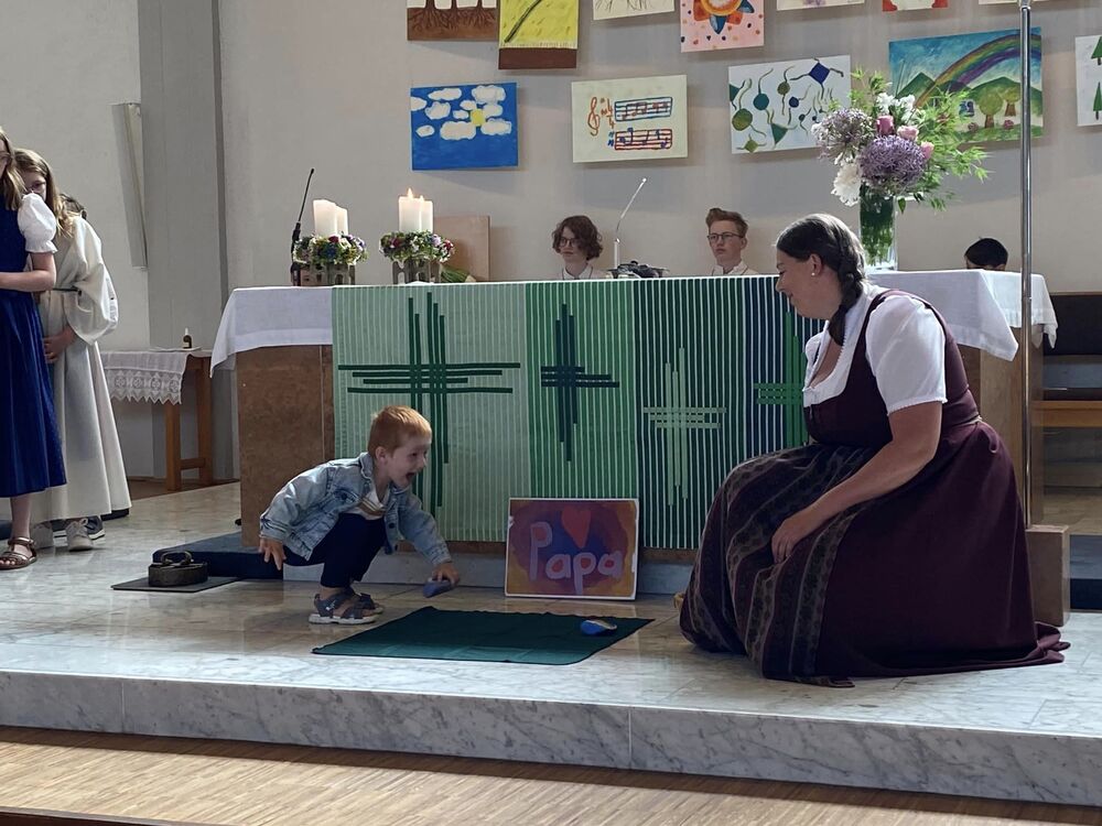 Ein Kind legt einen Stein vor den Altar nieder beim Familiengottesdienst zum Vatertag
