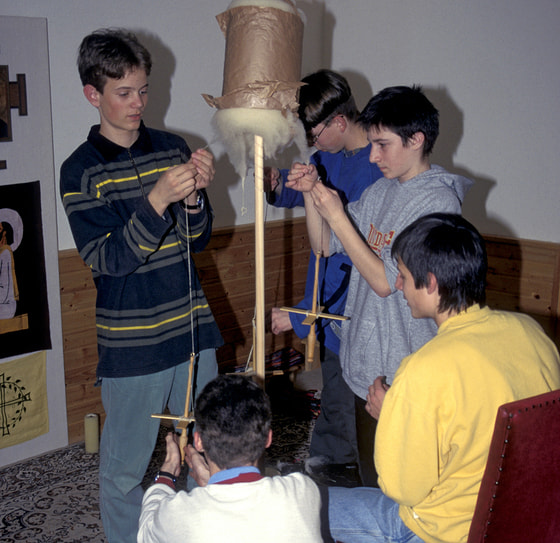 Die Runde spinnt Schafwolle mit Kreuzspindeln