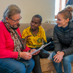 Biko sieht mit Maria Spernbauer und Julia Moser Fotos aus seiner Kindheit an.