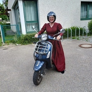 Eine Goldhaubenfrau mit Festkleid auf dem Motorolla  ohne Goldhaube aber mit Helm - zur Sicherheit.