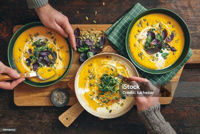 Men eating Vegan Creamy Roasted Pumpkin Soup on wooden background