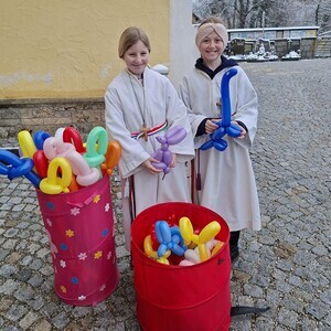Ministrantinnen teilen Luftballontiere aus.