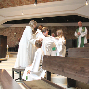 Auch die neuen Ministranten erhalten ihre Kleidung. Beim Anziehen helfen alle mit.