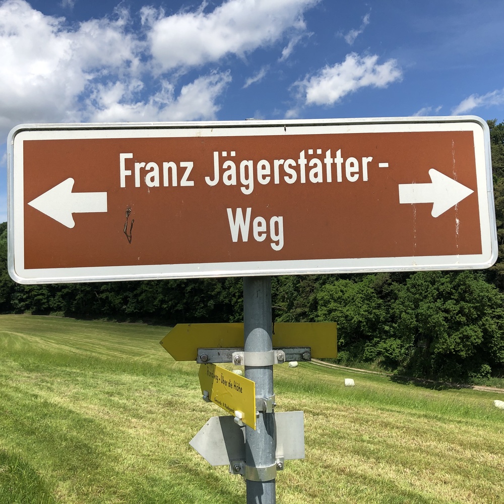 wegweiser mit Pfeilen nach recht und link mit der Aufschrift Franz Jägerstätter Weg