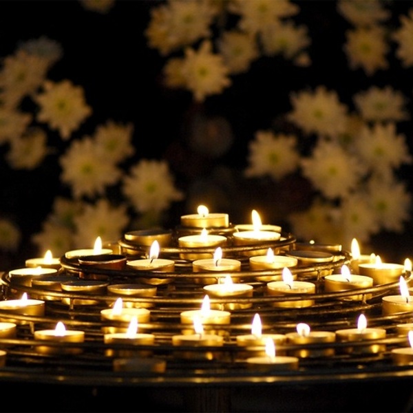 Teelichter auf spiraligem Metallgestell,  im Hintergrund sieht man zart weiße Blumen, die wie Sterne wirkenp