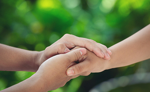 Couple holding hands in green meadow.