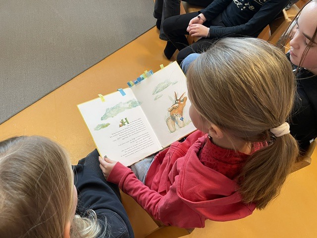 Schulkinder lesen mit den Kindergartenkindern