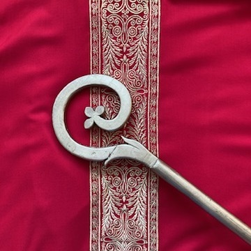 Bischofsstab liegt auf rotem goldbesticktem Gewandestickten