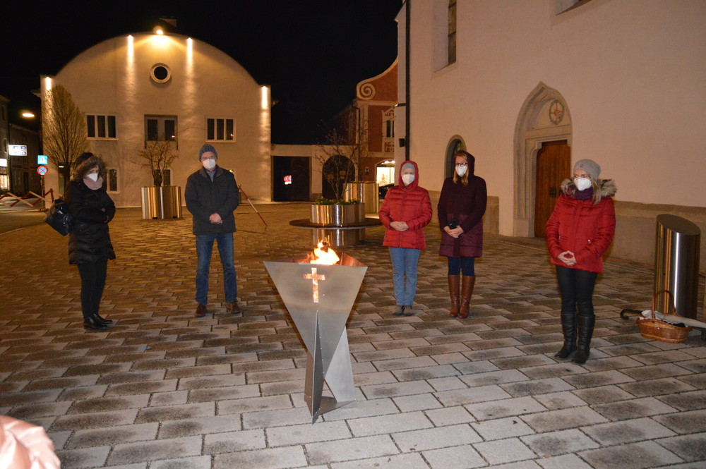 einige Personen stehen um die neue Feuerschale am Kirchenvorplatz in Perg