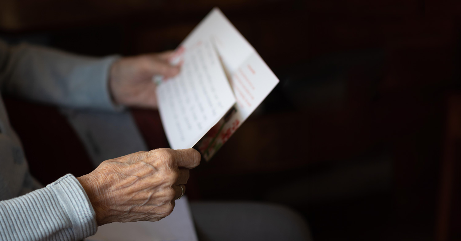 Ältere Person, die einen Text und eine Karte in Händen hält