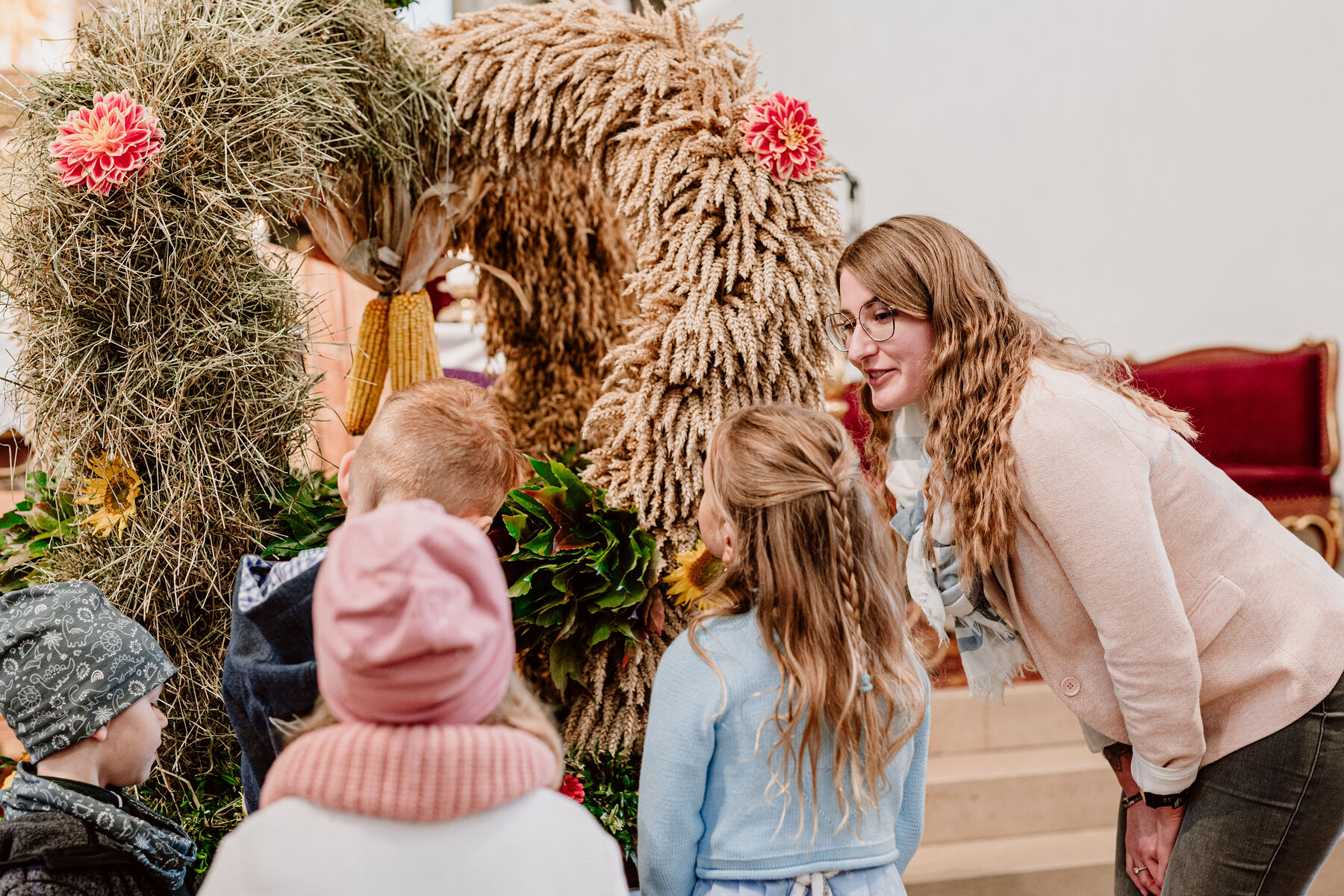 Tamara Rennleithner, Leiterin des Pfarrcaritas-Kindergartens und der Pfarrcaritas-Krabbelstube in Pichl bei Wels, zeigt den Kindern die Erntekrone in der Kirche.