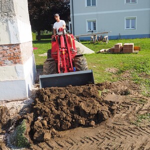 Andreas schafft gekonnt Erde beiseite, damit Schüttmaterial Platz hat.