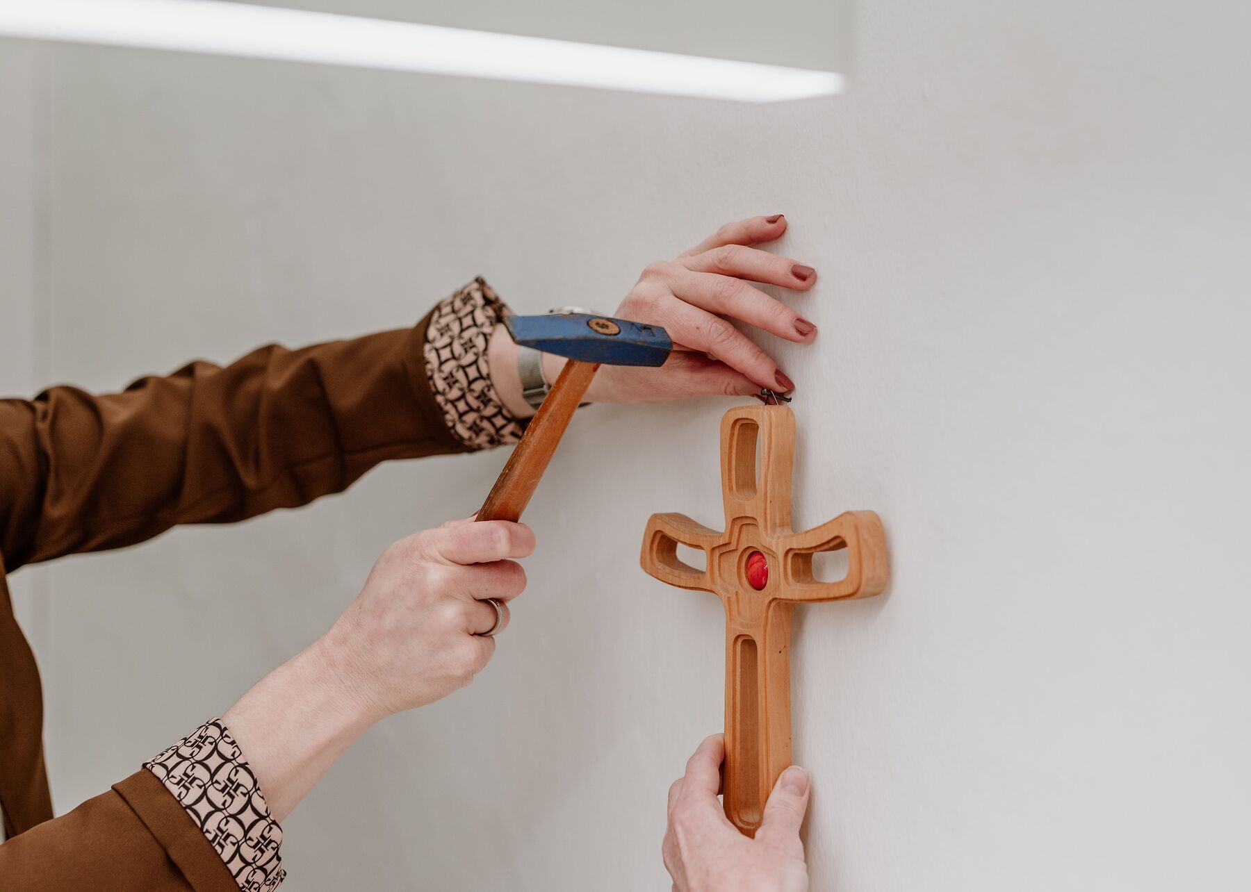Ein hölzernes Kreuz wird an der Wand befestigt.