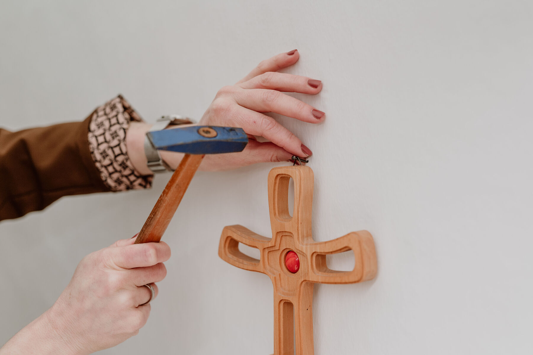 Ein hölzernes Kreuz wird an der Wand befestigt.