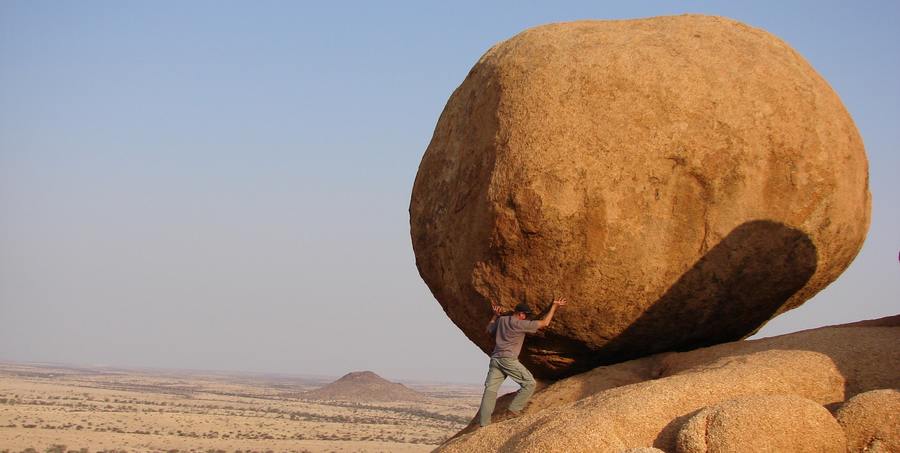 Fastenzeit und Ostern / vicky-sim-mj51pZwan9c-unsplash Mann bewegt einen Stein in der Wüste