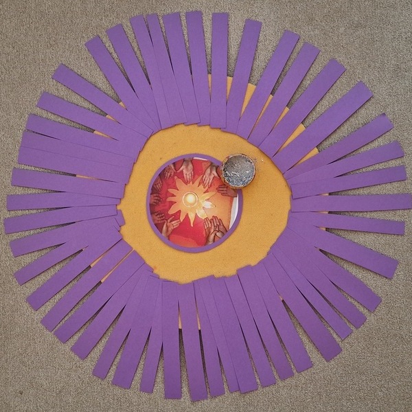 Eine Schale mit Asche im Zentrum eines gelben Kreises, umgeben von 40 strahlenförmig angeordneten lila Papierstreifen