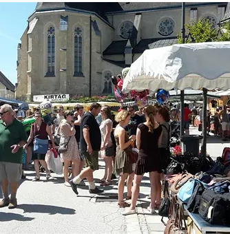 Leute am Kirtag, rechts Kirtagstand, im Hintergrund die Kirche