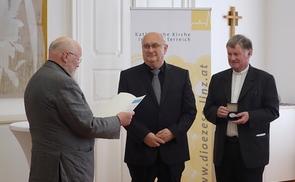 Franz Karl Prassl, Präsident der Österreichischen Kirchenmusikkommission, und Diözesanbischof Manfred Scheuer überreichen Domorganist Wolfgang Kreuzhuber die Auszeichnung                        